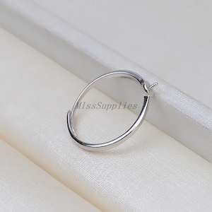 Könnte beinhalten: Ein silberner Ring mit einem kleinen Loch oben, geeignet zum Anbringen eines Anhängers oder Charms.