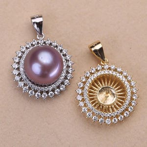 Puede incluir: Dos colgantes de plata y oro con un diseño redondo de cristal transparente. Un colgante presenta una perla morada en el centro.