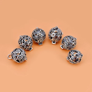 Può includere: Sei ciondoli in metallo argentato con intricati motivi floreali. I ciondoli sono rotondi e vuoti, con un delicato motivo traforato. Hanno un'apertura a cerniera e sono perfetti per aggiungere a gioielli o artigianato.