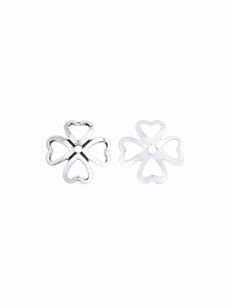May include: Two silver-toned metal flower-shaped bead caps with a hole in the center. The caps are made of four heart-shaped loops.