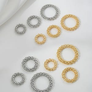 Op de afbeelding: Assortiment van kleine, ronde, gouden en zilveren ringen gemaakt van kleine kralen. De ringen zijn in verschillende maten.