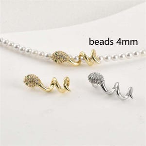 May include: Gold and silver-toned snake-shaped beads with a spiral design. The snake heads are encrusted with small, sparkling stones. The text "beads 4mm" is visible. These beads are ideal for jewelry making.