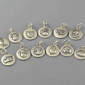 May include: Twelve gold-toned metal charms featuring the Chinese zodiac animals. Each charm is round and has a different animal engraved on it.
