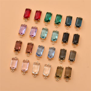 Pode incluir: Conjunto de contas retangulares de vidro coloridas com laços de conexão de metal dourado. As contas são de várias cores, incluindo vermelho, verde, azul, roxo, marrom e transparente.