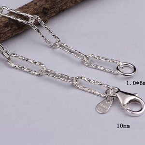 Pode incluir: Pulseira de corrente de prata com um design de elo retangular texturizado. A corrente tem 3,7 mm de largura e o fecho 10 mm de comprimento. O fecho &eacute; do tipo lagosta com um anel na extremidade.