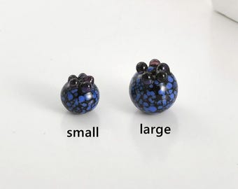 May include: Two blue glass marbles with black and purple speckles. The marble on the left is smaller than the marble on the right. The smaller marble is labeled "small" and the larger marble is labeled "large".