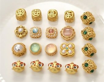 May include: A collection of 18 gold-tone charms with various designs, including squares with Chinese characters, round charms with different colored stones, and frog charms with red accents.