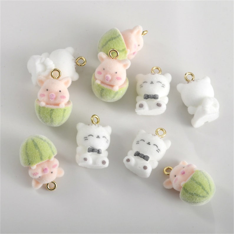 May include: Assortment of 10 colorful charms featuring cartoon pigs and cats. The charms are made of soft, plush material and have a gold-colored metal loop for attaching to jewelry or other crafts.
