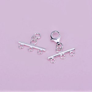 May include: Two silver-toned toggle clasps with three loops each. The clasp on the right has a lobster claw closure.
