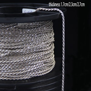May include: A spool of silver-colored rope with a twisted design. The rope is coiled around a black plastic spool. The text on the image reads "thickness 1.7cm/2.3cm/2.7cm".
