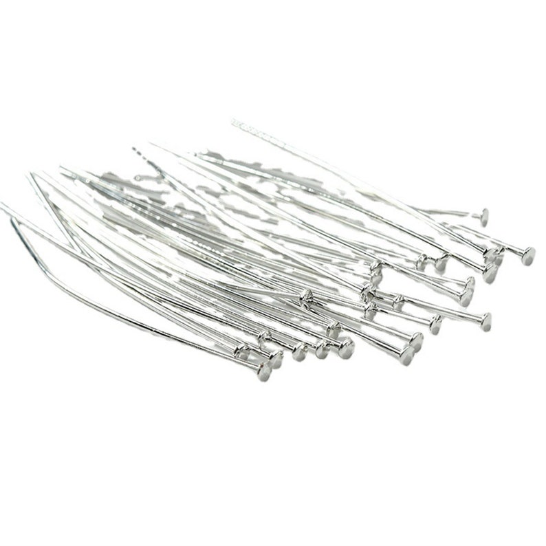 Puede incluir: Un mont&oacute;n de alfileres de cabeza redonda de color plateado. Los alfileres est&aacute;n dispuestos en un patr&oacute;n aleatorio y todos son del mismo tama&ntilde;o.