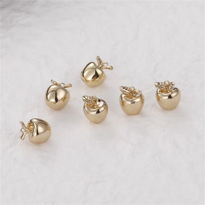 Puede incluir: Seis pequeños dijes dorados con forma de manzana, con tallos y hojas. Los dijes son muy reflectantes, con una superficie lisa y pulida. Estos dijes de manzana en miniatura son ideales para la fabricación de joyas u otros proyectos de artesanía.