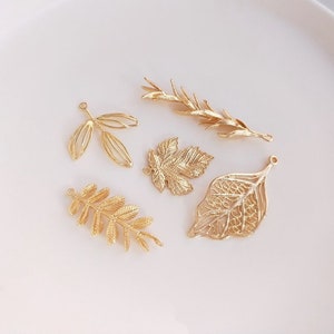 May include: Five gold-coloured metal leaf charms with intricate designs. The charms are perfect for jewellery making, scrapbooking, and other craft projects.