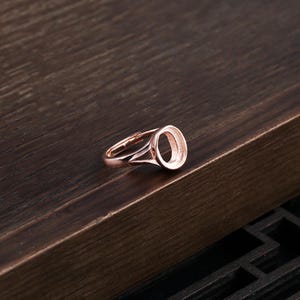 Pode incluir: Um anel de ouro rosa com uma configuração de bezel redonda. O anel é projetado para segurar uma pedra cabochão.