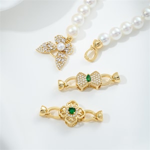 May include: Gold tone necklace with a pearl strand and three different charms: a butterfly with clear stones, a bow with a green stone, and a four-leaf clover with a green stone.