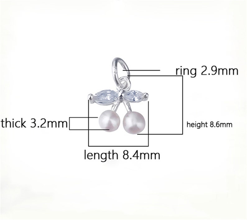 K&ouml;nnte beinhalten: Silberner Anh&auml;nger mit zwei wei&szlig;en Perlenkirschen und klaren Kristallbl&auml;ttern. Der Anh&auml;nger ist 8,4 mm lang, 8,6 mm hoch und 3,2 mm dick. Der Ring hat einen Durchmesser von 2,9 mm.