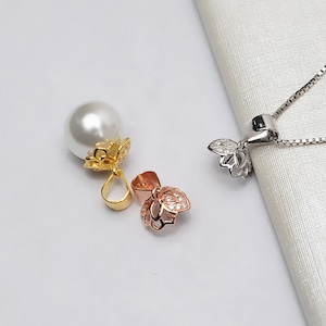 Puede incluir: Tres cierres de perla en oro, oro rosa y plata. Cada cierre presenta un delicado diseño floral con pequeñas piedras transparentes.