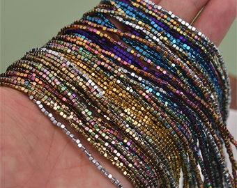 May include: A strand of iridescent square beads in various colors, including silver, gold, blue, purple, and green. The beads are small and uniform in size, creating a shimmering effect.