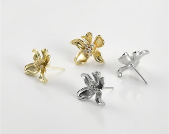 May include: Three pairs of flower-shaped earring findings with clear rhinestones. The findings are in gold and silver tones.