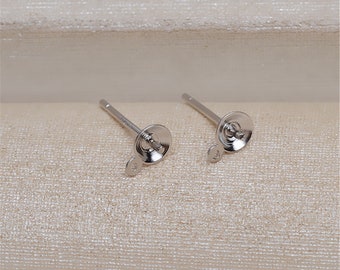 May include: Two silver earring posts with a small loop on the back of each post. The posts are designed to hold a gemstone or other jewelry.