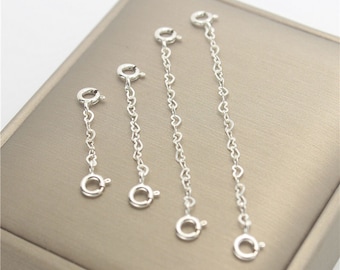 Può includere: Tre estensori per catena a forma di cuore in argento di diverse lunghezze. Gli estensori sono realizzati con una catena delicata con un moschettone a un'estremità e un anello di giunzione all'altra.