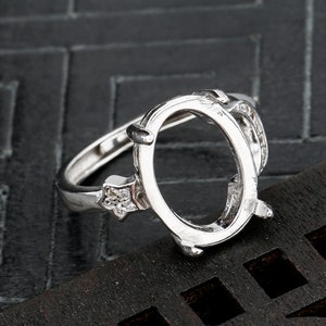 May include: Silver ring with an oval-shaped setting and small cubic zirconia stones on the band.