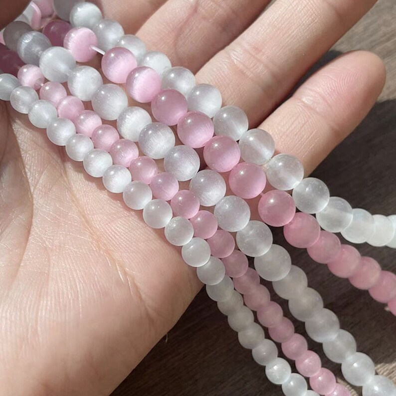 May include: A strand of white and pink gemstone beads. The beads are round and have a smooth, polished finish.