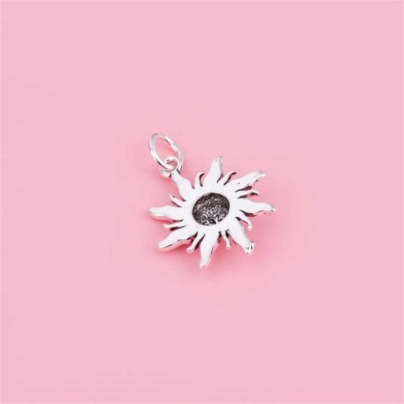 Puede incluir: Encanto de plata en forma de sol con un dise&ntilde;o detallado. El encanto tiene un bucle en la parte superior para sujetarlo a una pulsera o collar.