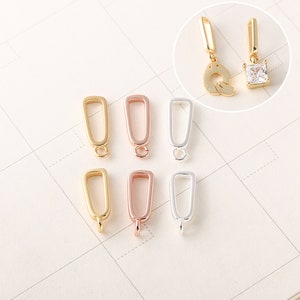 May include: Six gold, rose gold, and silver jump rings with a rectangular shape and a small loop at the top. The jump rings are arranged in two rows of three.