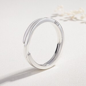 Pu&ograve; includere: Un anello d'argento con un design a doppia fascia. L'anello &egrave; contrassegnato con "S925" all'interno.