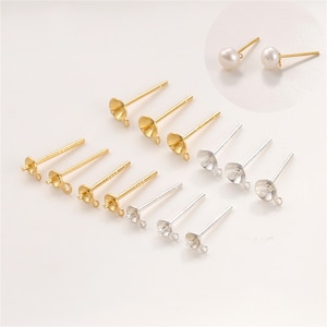 May include: An assortment of gold and silver-colored earring posts with various cup and peg designs. A pair of pearl stud earrings is also shown. These jewelry findings are ideal for DIY earring projects.