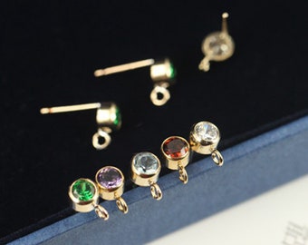 May include: Assortment of six gold-toned earring findings with different colored gemstones. The findings have a loop at the top for attaching to earrings.