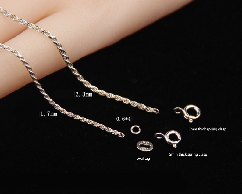 May include: Close-up of silver jewelry components, including two twisted rope chains, measuring 1.7mm and 2.3mm in thickness. Also shown are two 5mm thick spring clasps, an oval tag, and a small ring. The text "ITALY" is visible on the tag.