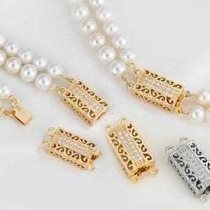 Può includere: Quattro chiusure in tono oro e argento con un designo a filigrana decorativo e accenti di cristallo trasparente. Le chiusure sono rettangolari e hanno due anelli su ogni lato.