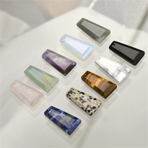 Peut inclure: Assortiment de dix pendentifs en pierres précieuses de différentes couleurs et formes. Les pendentifs sont tous rectangulaires et ont une finition lisse et polie. Les couleurs comprennent l'améthyste, le noir, le bleu, le brun, le vert, le gris, le rose, le blanc et un brun et blanc moucheté.