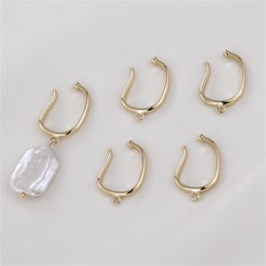 May include: Five gold-toned metal earring hoops with a smooth, rounded finish. The hoops are designed to be used as earring findings for attaching charms or other jewelry components.