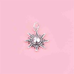 Puede incluir: Un colgante de sol de plata con un dise&ntilde;o detallado. El sol tiene un centro redondo y rayos que se extienden hacia afuera.