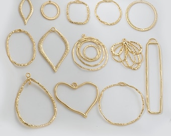 May include: A set of 13 gold-toned metal pendant blanks with various shapes, including circles, ovals, squares, hearts, and a teardrop. The blanks have a textured surface and are ready for crafting.