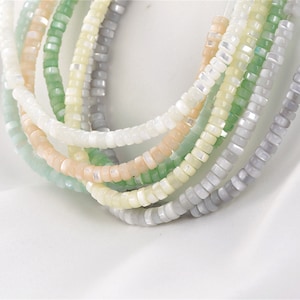 May include: A set of six strands of beads, each strand is made of small, square-shaped beads in a different pastel color. The colors are light green, light blue, light pink, white, gray, and beige.