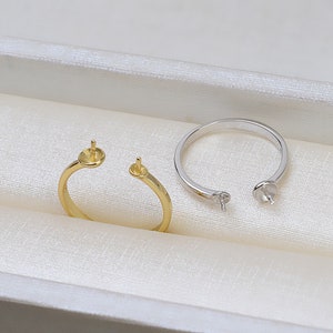 Può includere: Due anelli con una montatura per perle. Un anello è d'oro e l'altro è d'argento.