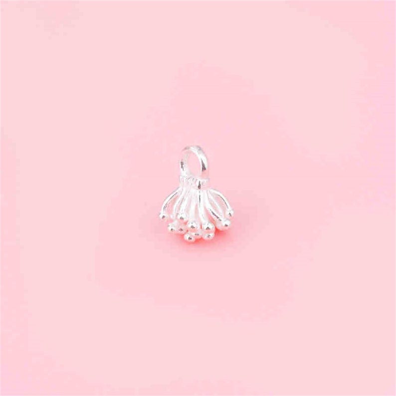 May include: Silver charm with a delicate, flower-like design. The charm has a loop at the top for attaching to a bracelet or necklace.