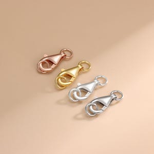 May include: Three lobster claw clasps in different metal finishes: gold, rose gold, and silver. These clasps are commonly used for jewelry making.