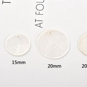 May include: Four white, round, shell-like, decorative pieces with a hole in the centre. The pieces are 10mm, 15mm, 20mm, and 20mm by 15mm in size.
