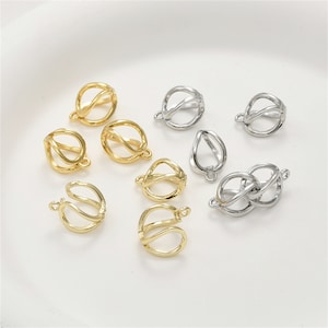 May include: A collection of gold and silver metal jewelry findings. The findings are shaped like a circle with a loop on the top. The findings are used to make necklaces, bracelets, and earrings.