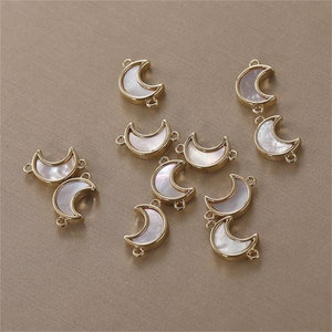 May include: A set of ten gold-toned metal moon charms with white mother-of-pearl inlays. The charms have two jump rings for attaching to jewelry.