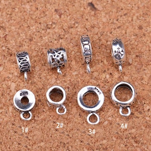 Op de afbeelding: Acht zilverkleurige metalen kralenspacers met verschillende ontwerpen. De spacers zijn genummerd van 1 tot en met 4.