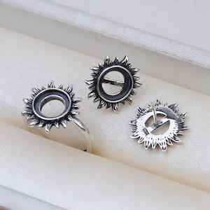 Puede incluir: Tres blancos de anillo y pendientes en forma de sol de plata. El blanco de anillo está sobre una superficie blanca. Los blancos de pendientes están sobre una superficie blanca. Los blancos de pendientes tienen un poste en la parte posterior.