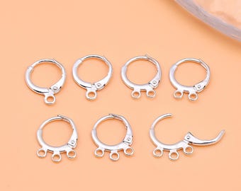 May include: A collection of silver-colored earring findings. The findings include various styles of hinged hoops, some with multiple loops for attaching charms or beads. The metal has a bright, reflective finish.