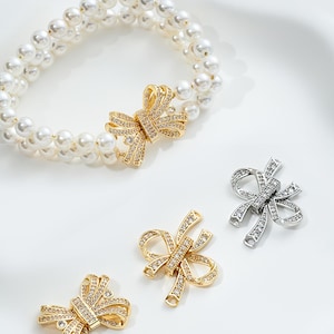 Peut inclure: Quatre fermoirs en forme de nœud or et argent avec des strass transparents. Les fermoirs sont conçus pour être utilisés comme fermoirs de bijoux.