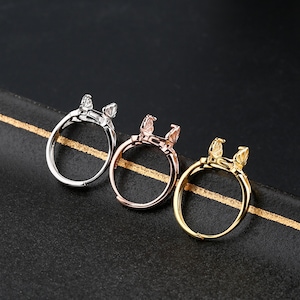 May include: Three adjustable ring settings in silver, rose gold, and gold. Each ring has a bezel setting for a cabochon stone.